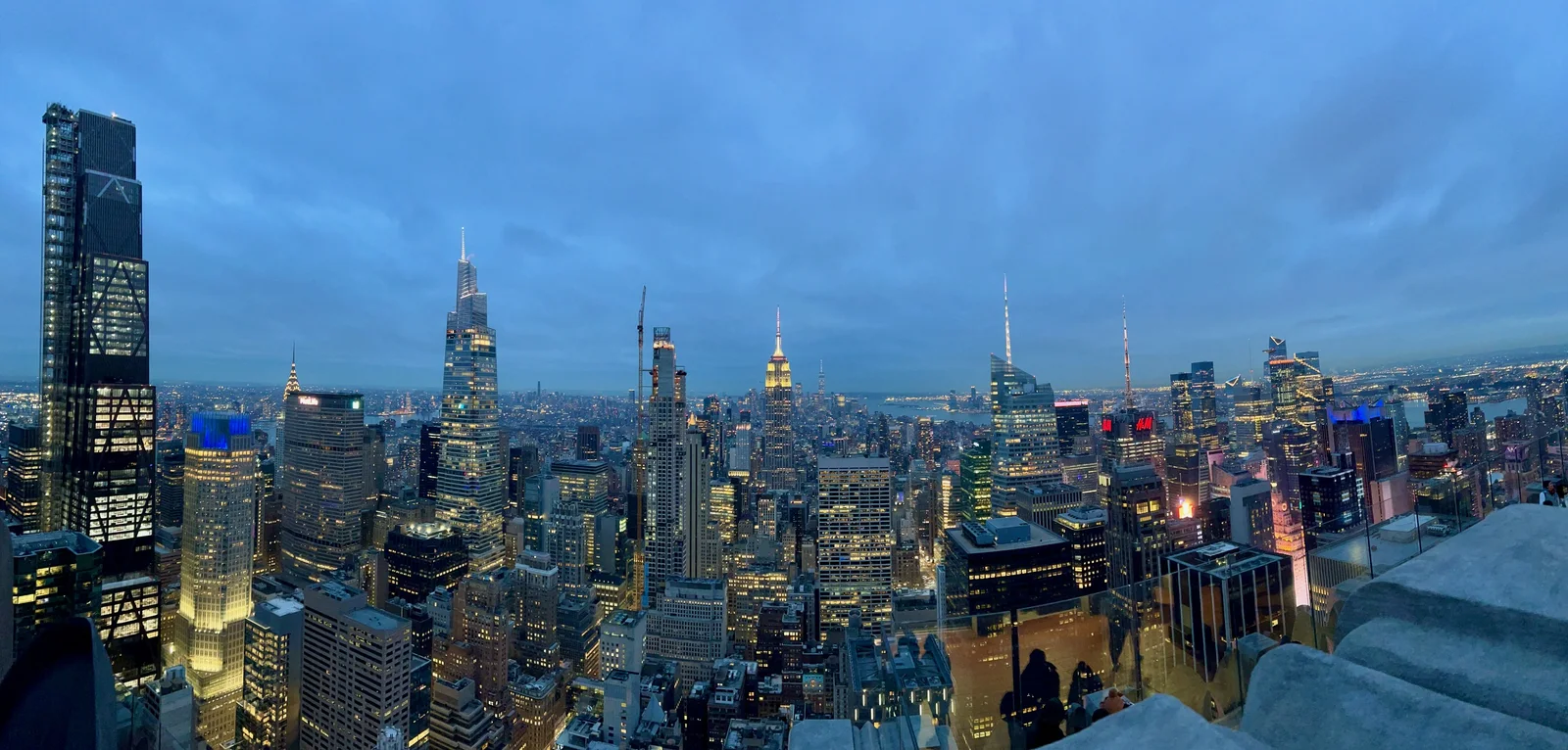 Panorama de Manhattan au crépuscule, avec l’Empire State Building illuminé au centre.